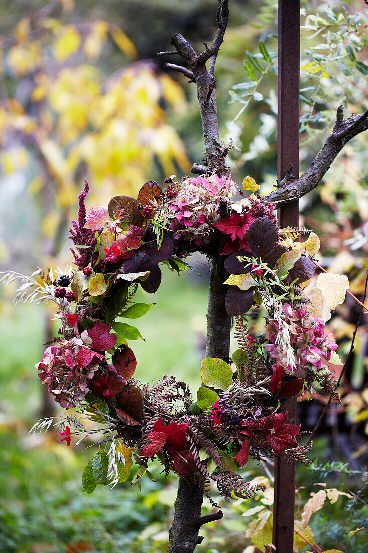 Herbstkranz aus bunten Blättern und Beeren im Garten