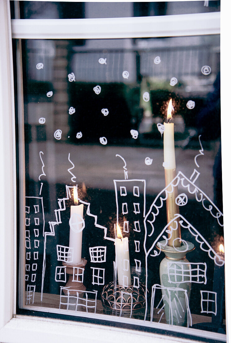 Weihnachtliche Fensterdekoration und brennende Kerzen