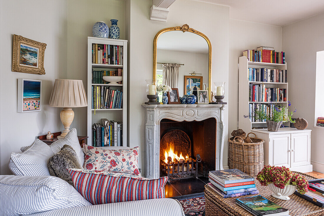 Traditionelles Wohnzimmer mit Kamin, Bücherregalen und gestreiftem Sofa