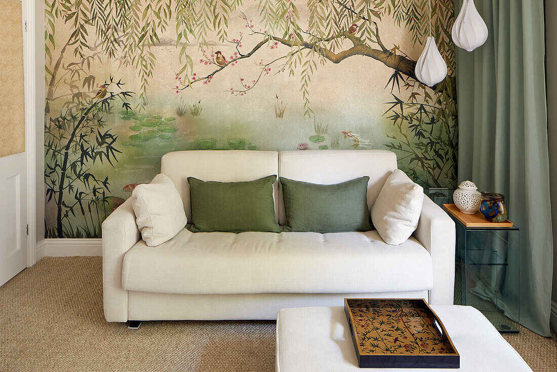 White sofa in front of artistic mural wallpaper with a landscape motif