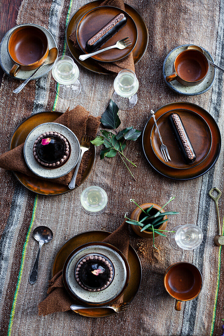 Table setting with ceramic crockery and chocolate desserts on a rustic tablecloth