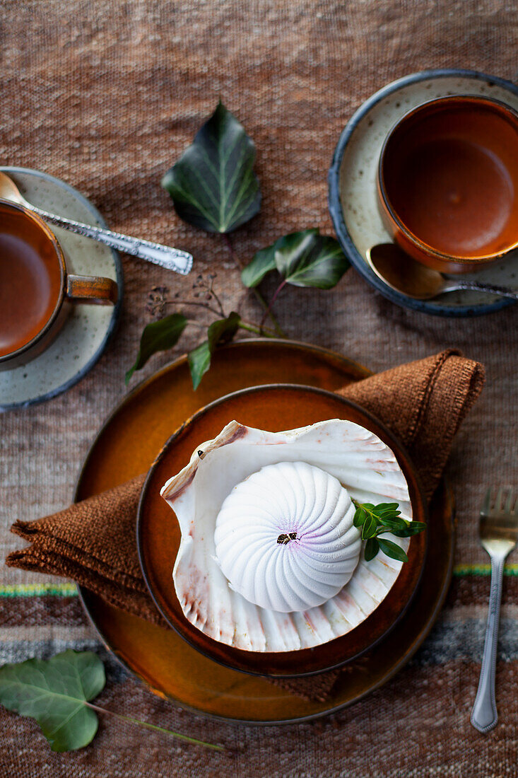 Gedeckter Tisch mit Dessert in Muschelschale und Teetassen