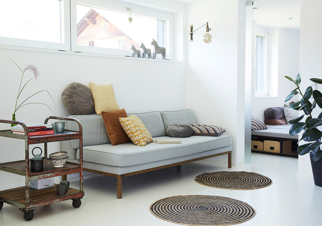 Bright living area with grey sofa, serving trolley and round rugs