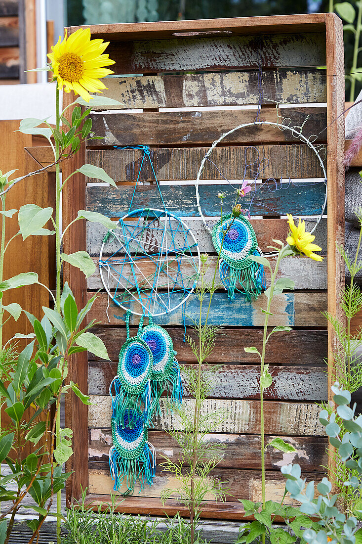 Dreamcatcher with crocheted peacock feathers in a rustic wooden box