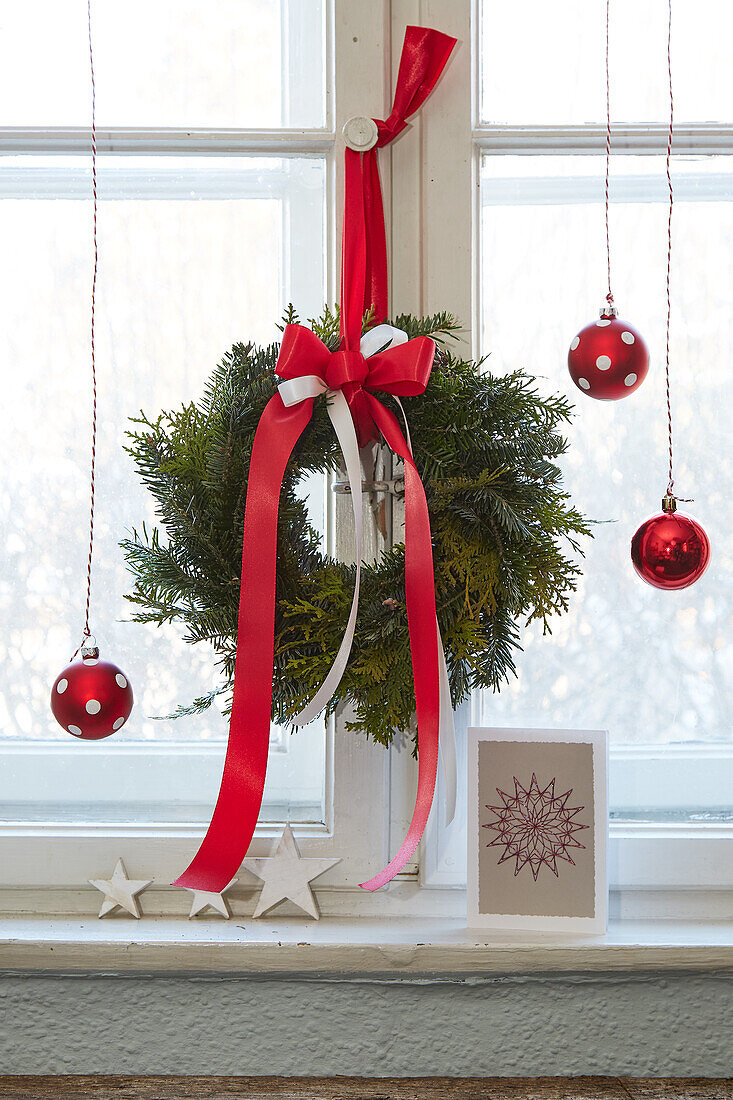 Christmas window decoration with wreath and red baubles