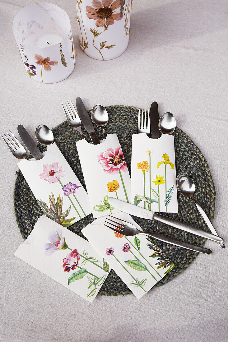 Table with floral cutlery bags and lanterns with flowers