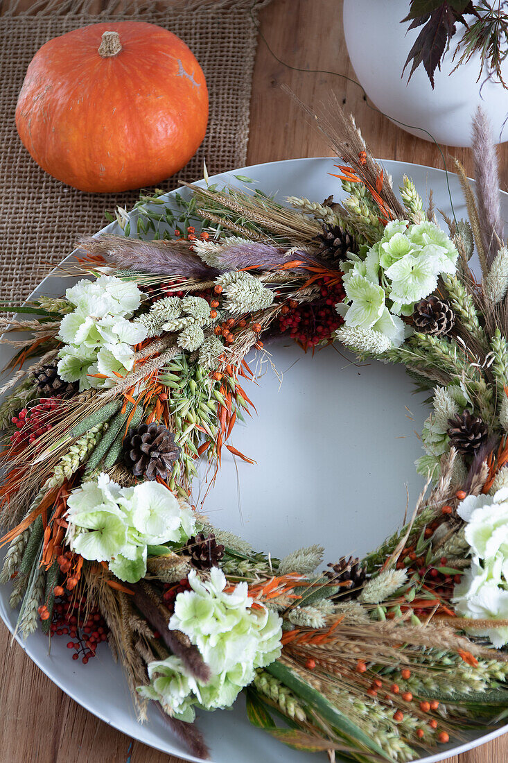 Autumn wreath made from dried flowers, pumpkin next to it