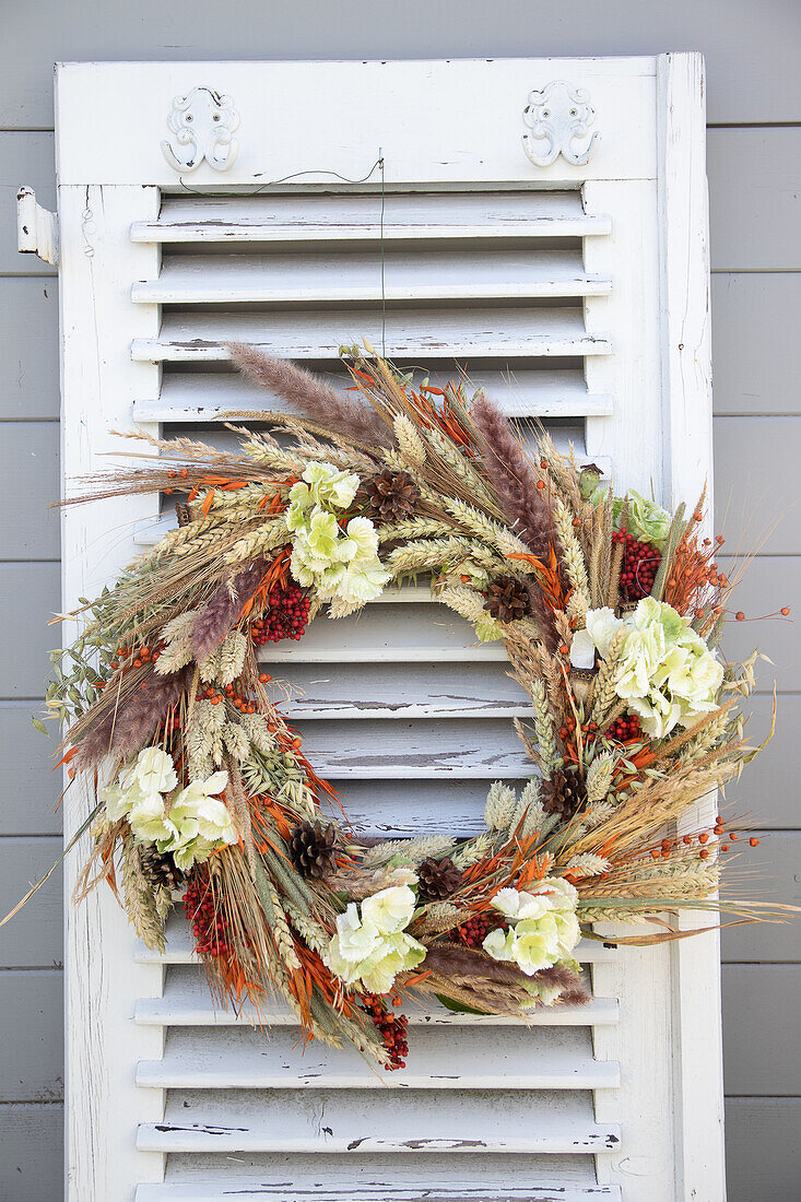 Herbstkranz aus Trockenblumen an Vintage-Fensterladen im Shabby-Chic-Look