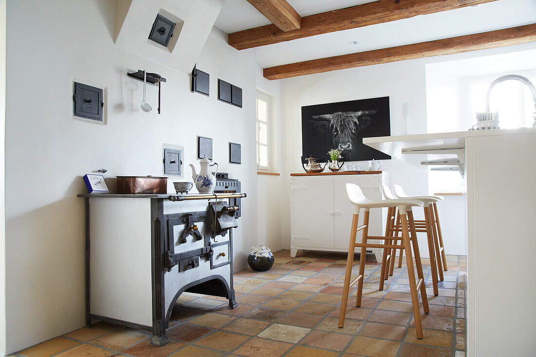 White kitchen with modern bar stools at the counter and antique cooker