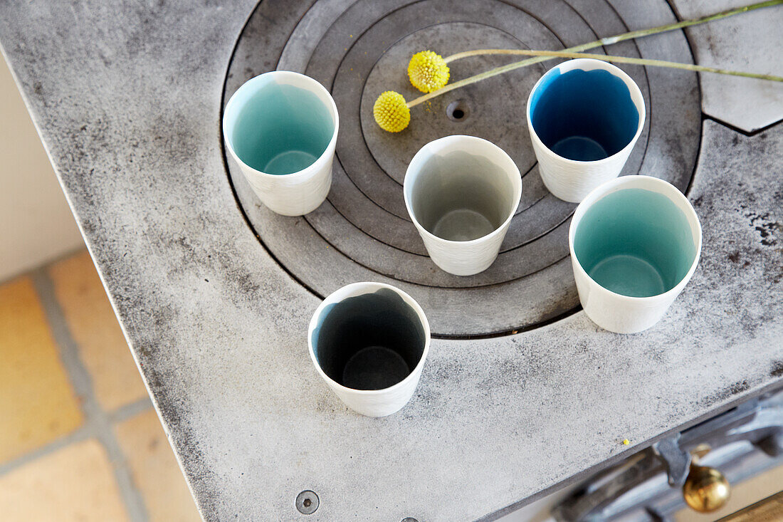 Ceramic mugs in different colours on an old cooker