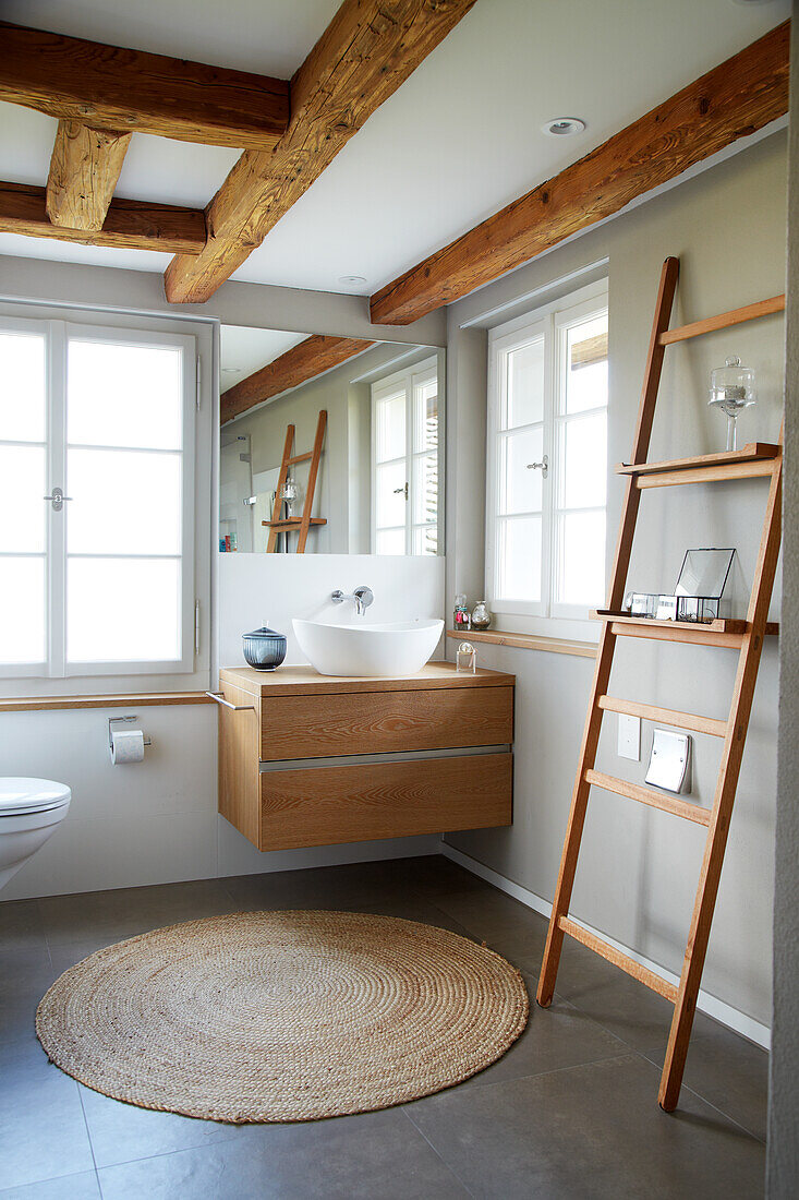 Bathroom with ladder, round carpet and ceiling beams