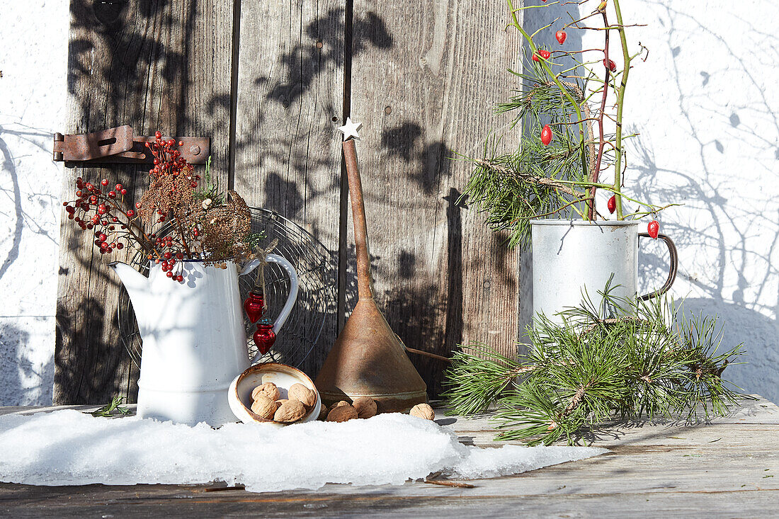 Winter decoration with twigs, berries and walnuts on a snow-covered wooden bench