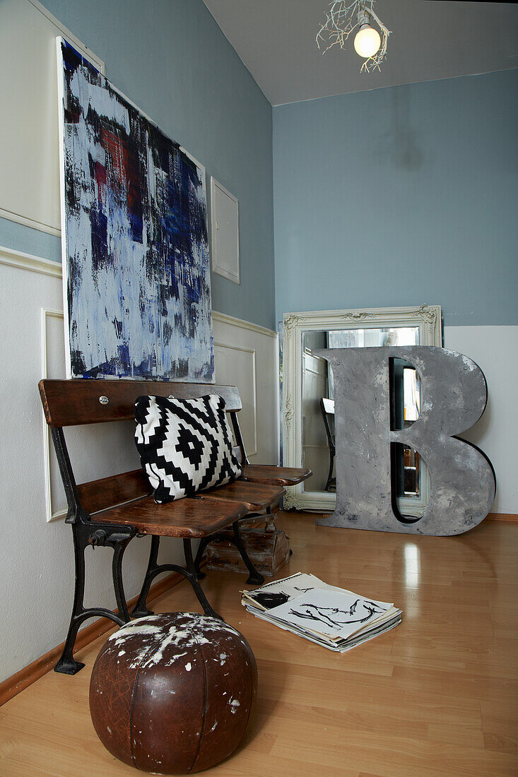 Vintage bench, above it modern art in the room with blue-white walls