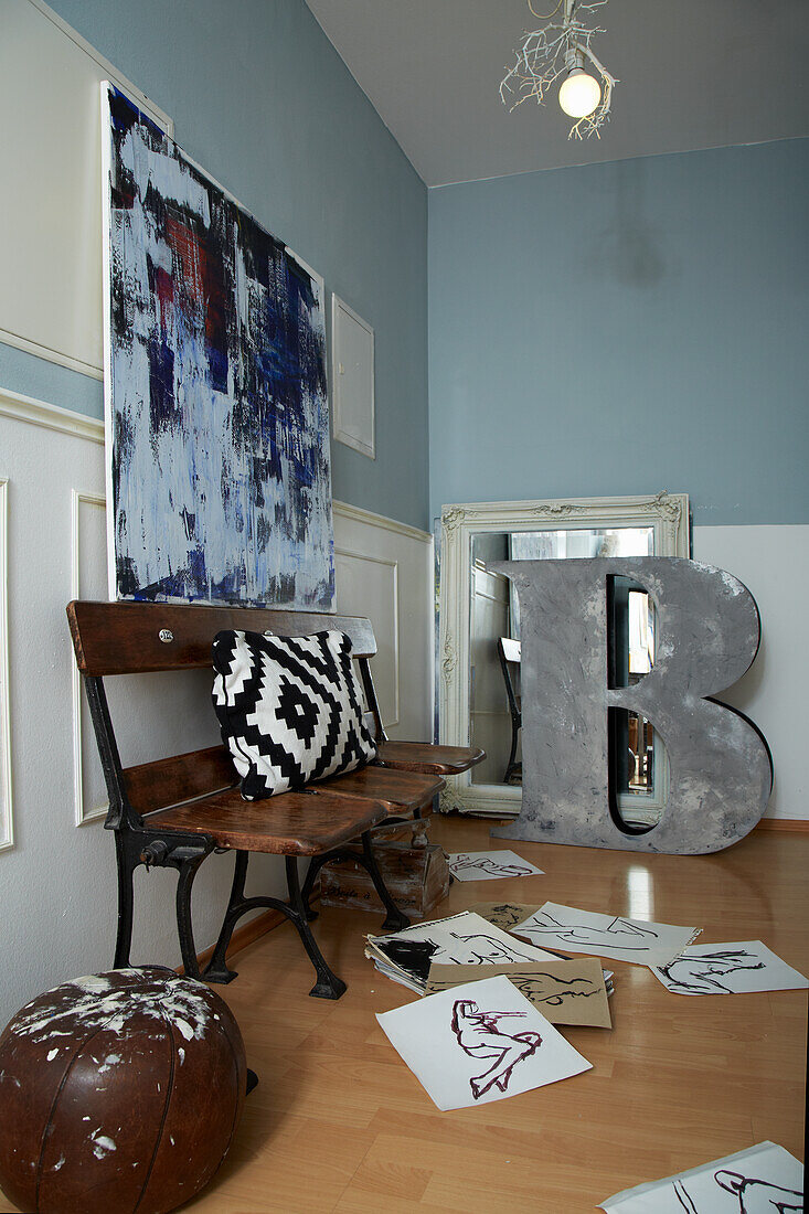 Vintage Bank, darüber moderne Kunst im Zimmer mit blau-weißen Wänden, Zeichnungen auf dem Boden
