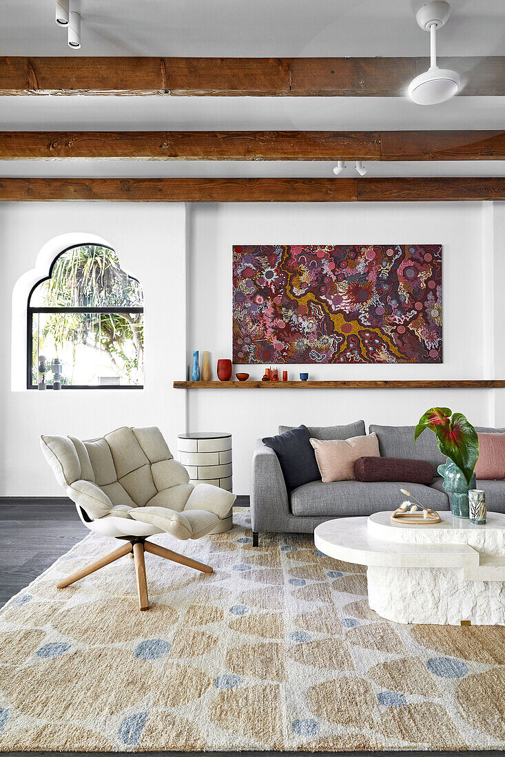 Lounge mit Designer-Sessel, Couchtisch und Sofa, moderne Kunst über Holzablage