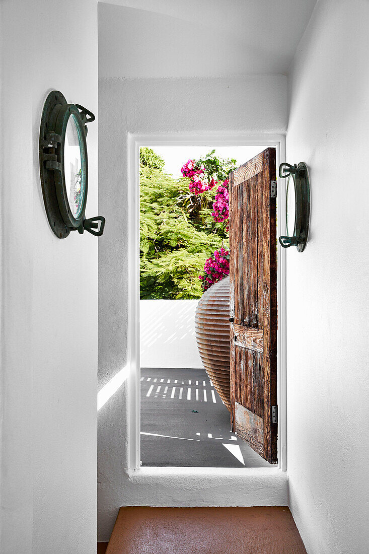 Narrow, white-painted hallway with wooden door open to the roof terrace