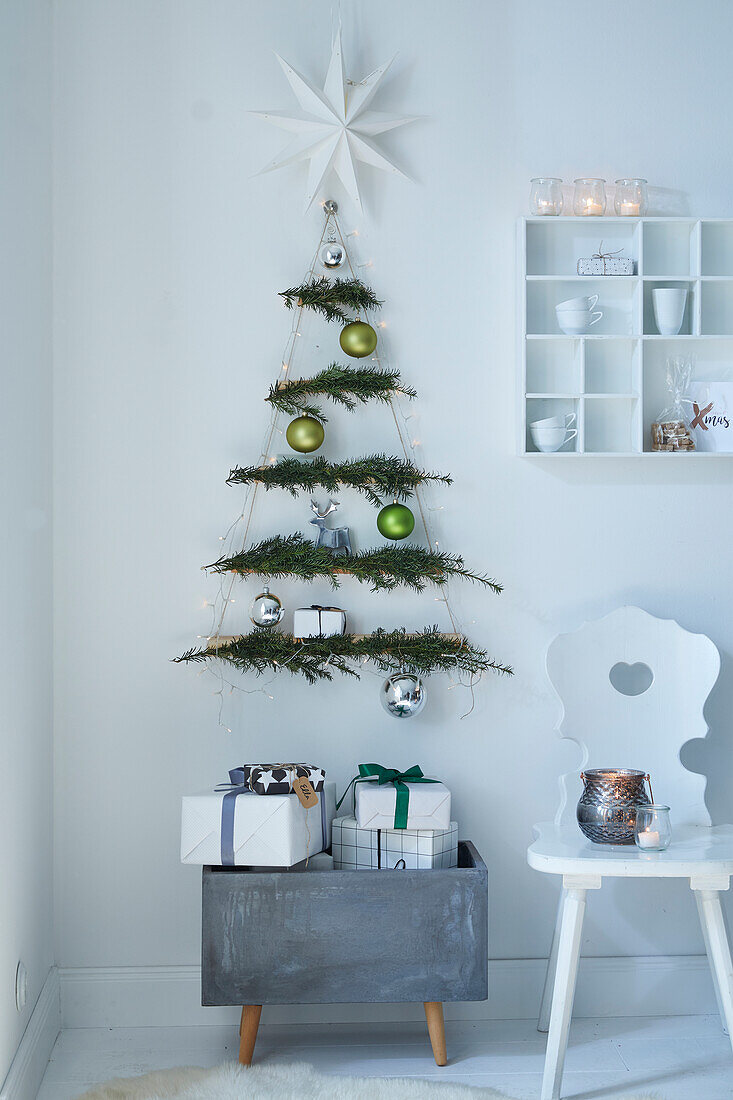 Modern DIY Christmas tree made of twigs with fairy lights on a white wall