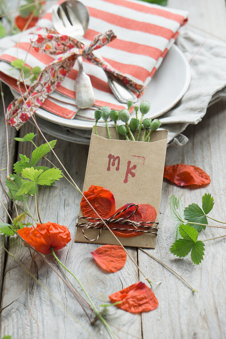 Place cards with stamped initials, decorated with poppies, poppy pods and strawberry vines