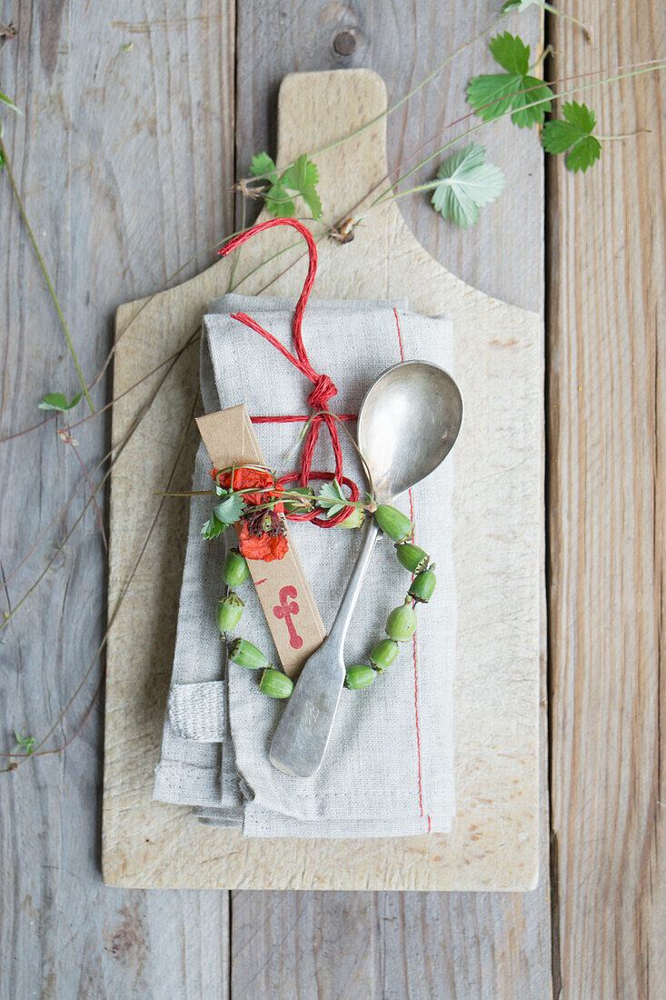 Napkin with name card, silver spoon, and wreath of poppy pods