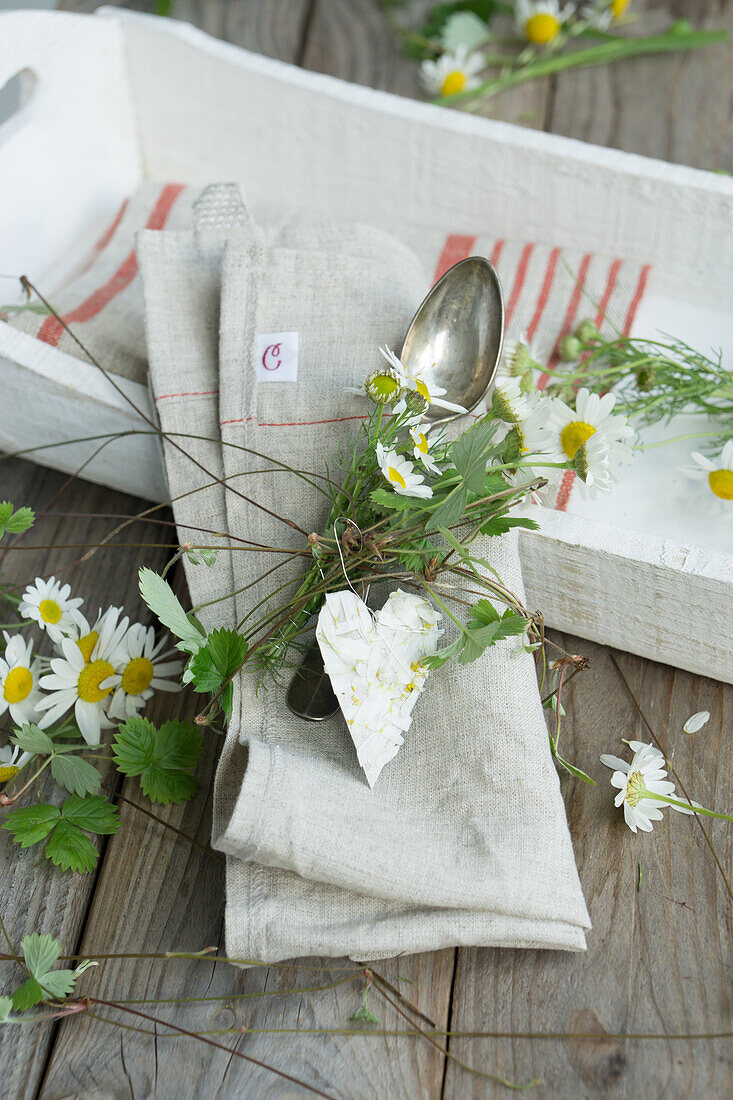 Serviette mit Kamillensträusschen, Herz aus Kamillenblüten, Erdberranken und Silberbesteck