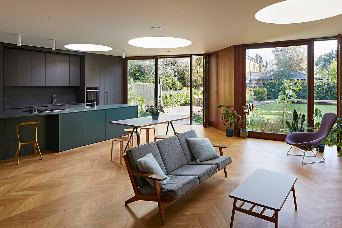 Kitchen, dining area, and seating area in an open-plan living room with parquet flooring and round skylights