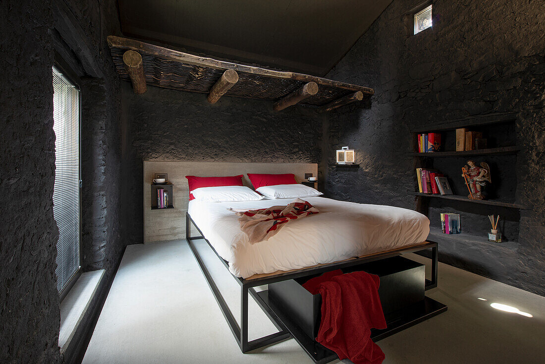 Schlafzimmer mit schwarz strukturierten Wänden und freiliegenden Deckenbalken