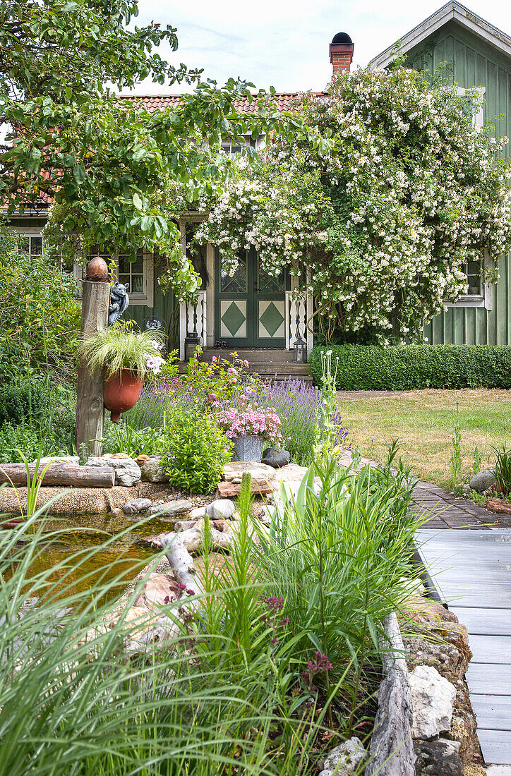 Garten mit Teich und Blick auf grün gestrichenes Wohnhaus