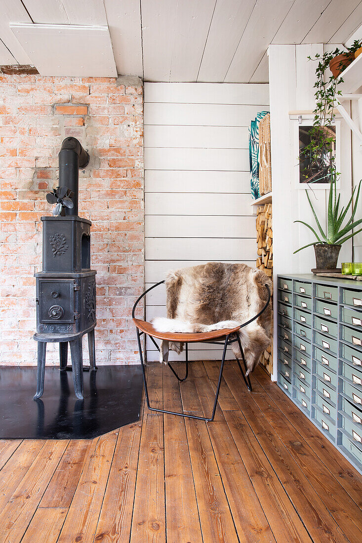View of fireplace in front of brick wall, chair with fur and apothecary cupboard