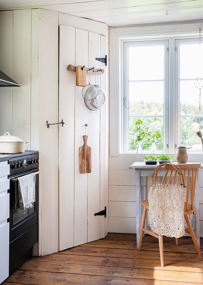 Wooden chair and table in a light-colored kitchen with white country house doors