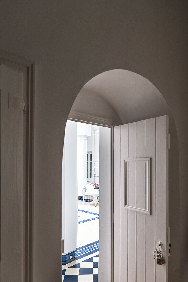 White archway and wooden door, view of tiled courtyard