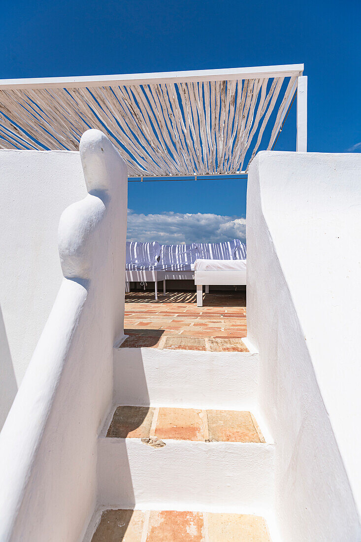 Treppe zur überdachten Terrasse mit Lounge-Möbeln