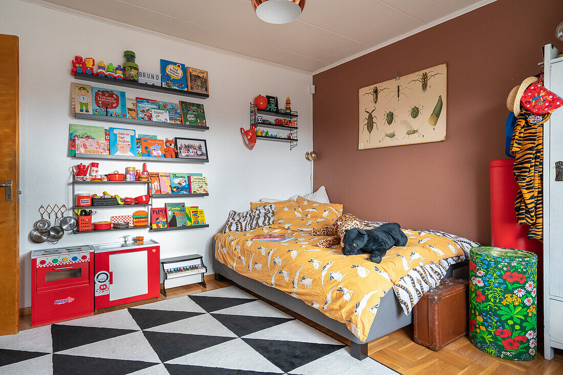 Bett, Regale mit bunten Büchern und Spielküche im Kinderzimmer