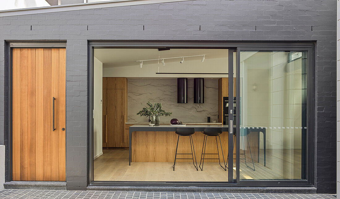 View from the courtyard into the kitchen with wooden fronts and kitchen island