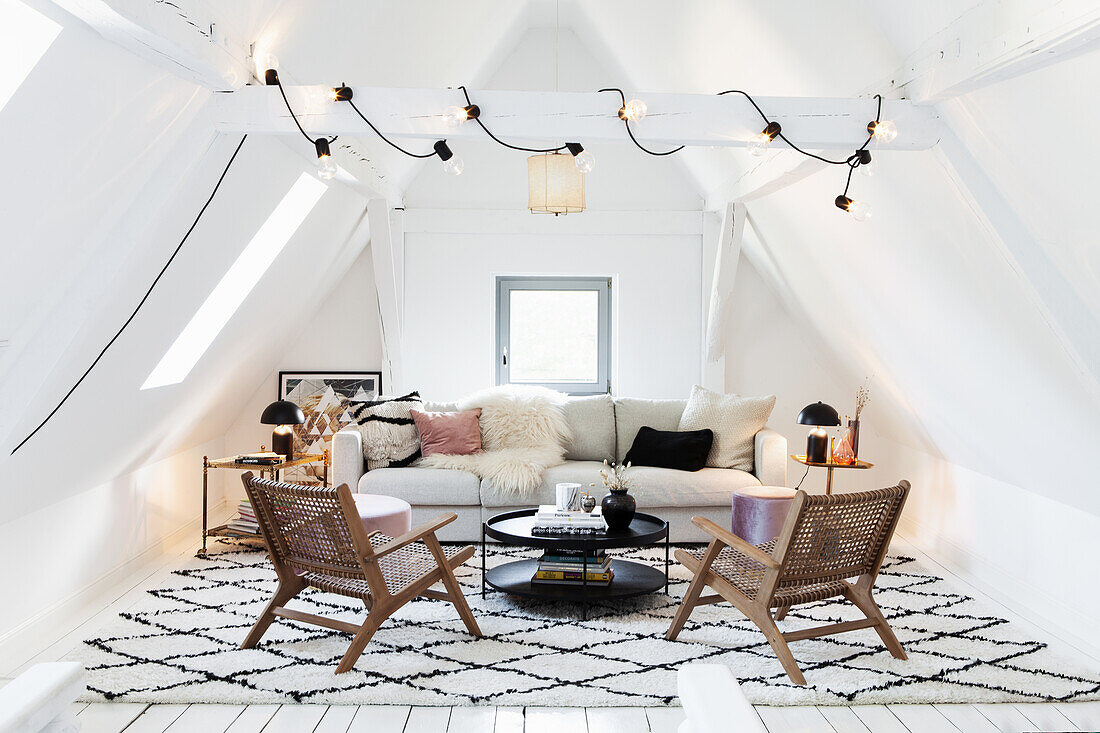 Attic living room with rattan armchairs, light-colored couch and patterned carpet