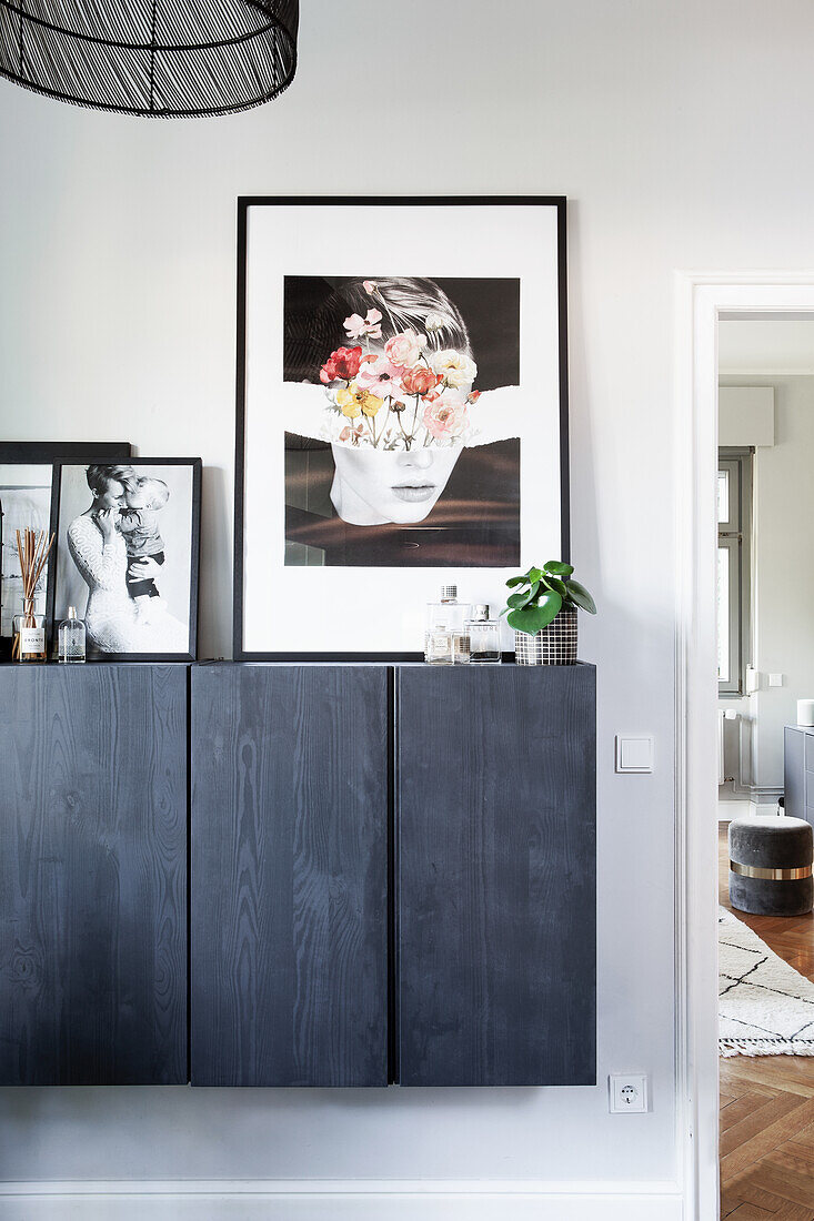 Floating chest of drawers with black wooden front and black and white photographs