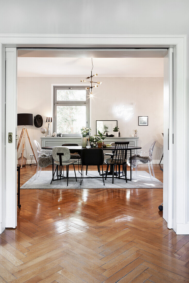 Dining room with assorted chairs and wooden table, herringbone parquet flooring, Sputnik lamp