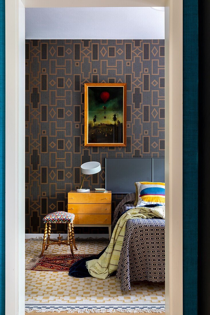 Blick ins Schlafzimmer - Tapete mit geometrischem Muster, Kunstwerk über Nachtschränkchen und Bett