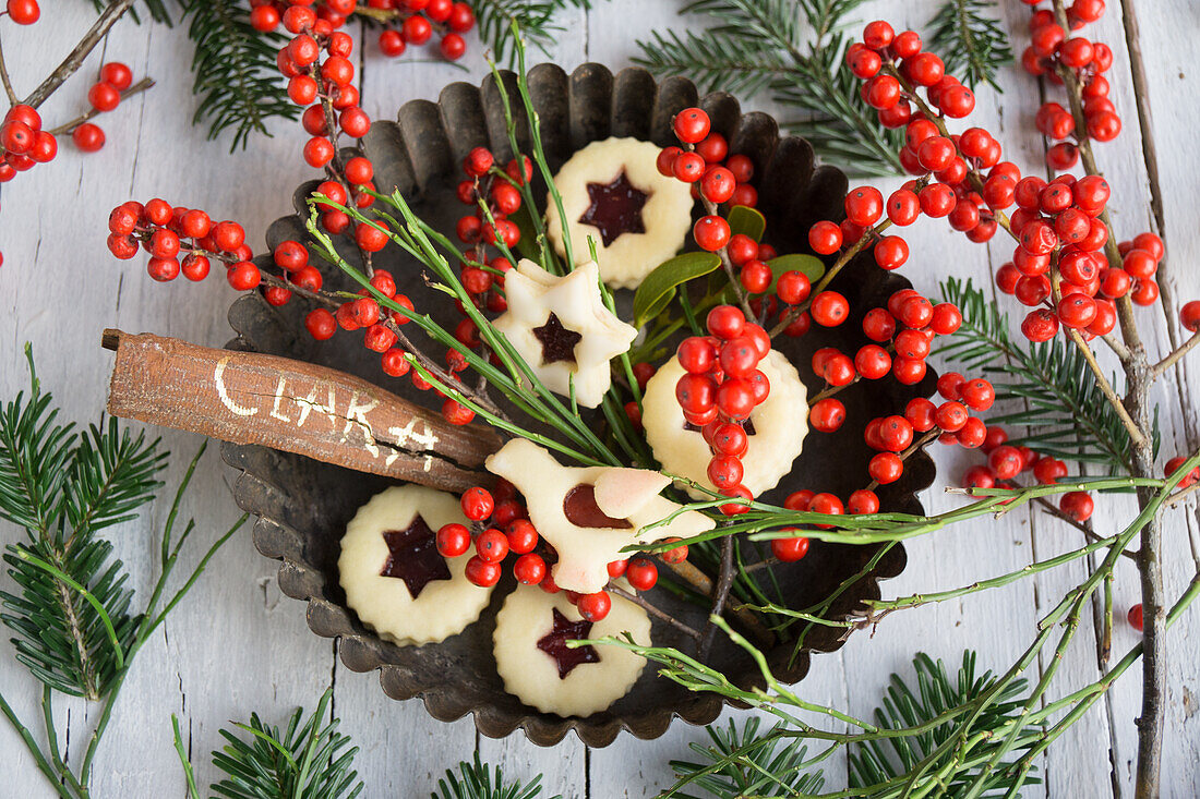 Spitzbuben, bird biscuits, holly berries, blueberry twigs and cinnamon stick in old baking tin