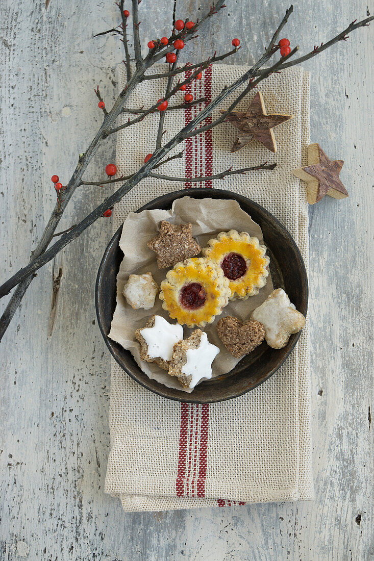 Baking tin with assorted cookies on a dish towel with holly and wooden stars