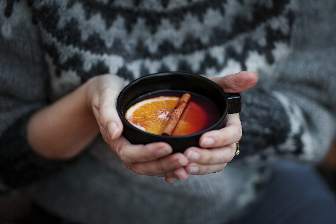 Hands holding cup with Glögg (Scandinavian mulled wine)