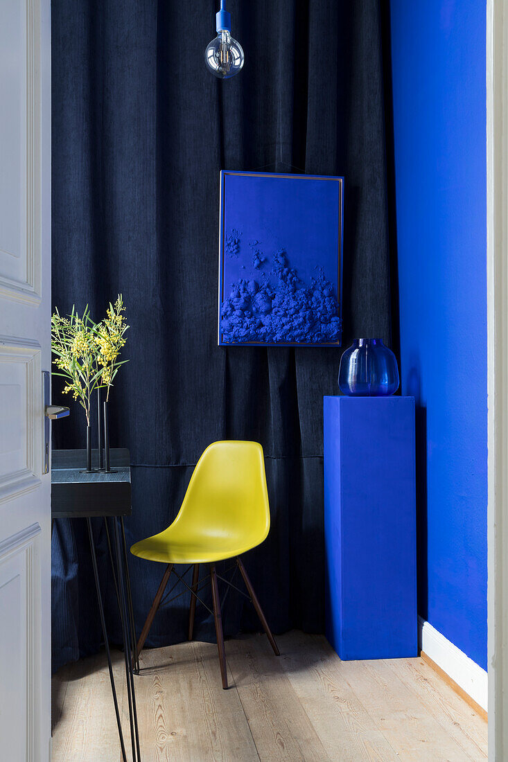 Yellow chair in front of dark blue curtain in room with bright blue wall