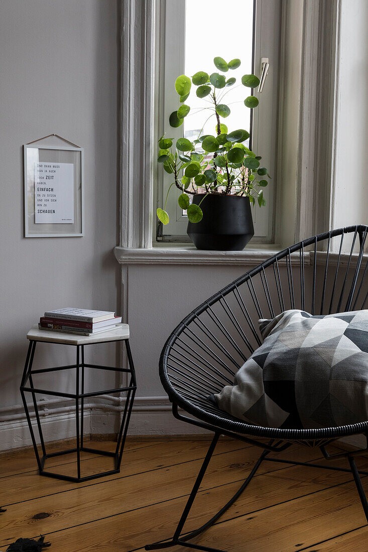 Side table and chair in the corner of a room with plant on the windowsill
