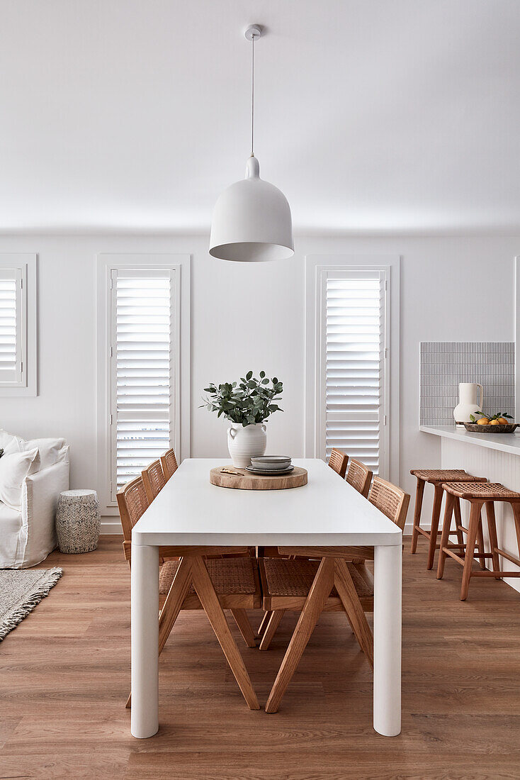 An open-plan kitchen and a dining room in a modern Scandi-style with plantation shutter and an oak wood floor