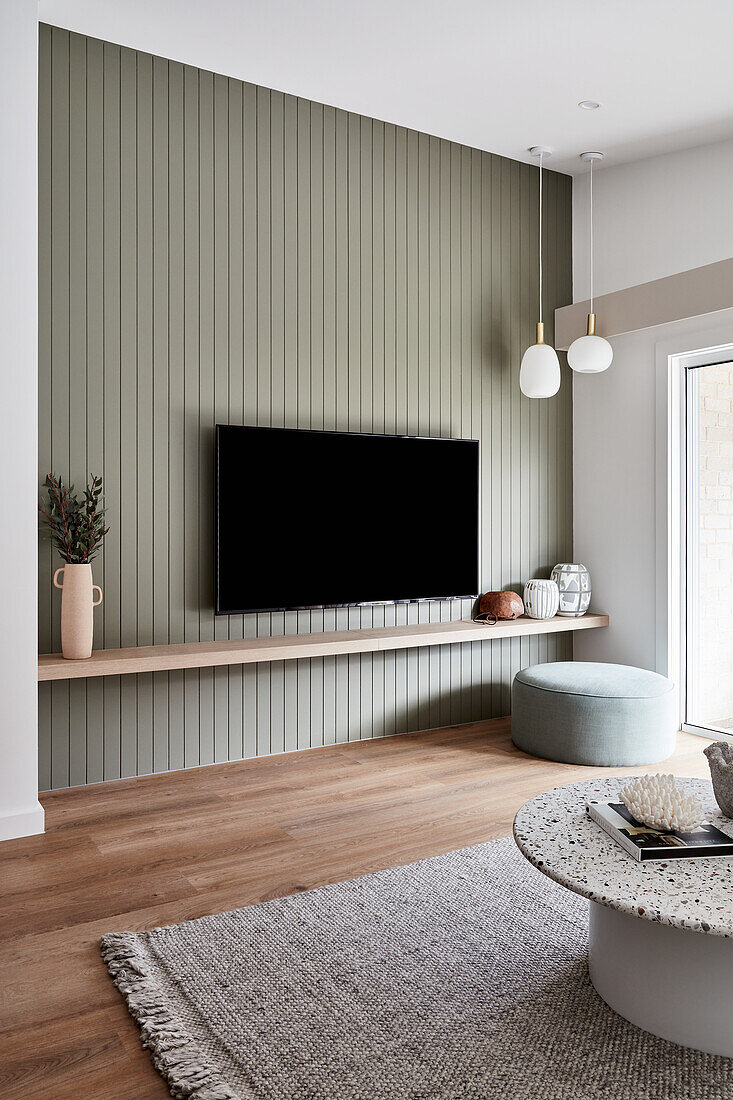 Modernes Wohnzimmer im Scandi-Stil mit Terrazzo-Couchtisch, Eichenboden und Flachbildfernseher an getäfelter Funktionswand