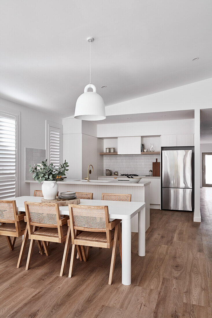 An open-plan kitchen and living room in a modern Scandi style with white furniture, golden fittings and an oak wood floor