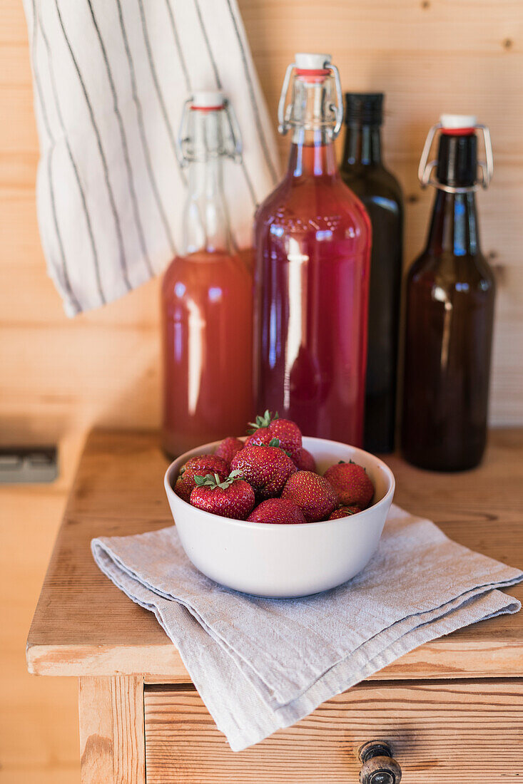Frische Erdbeeren und selbstgemachter Sirup auf Holzschränkchen