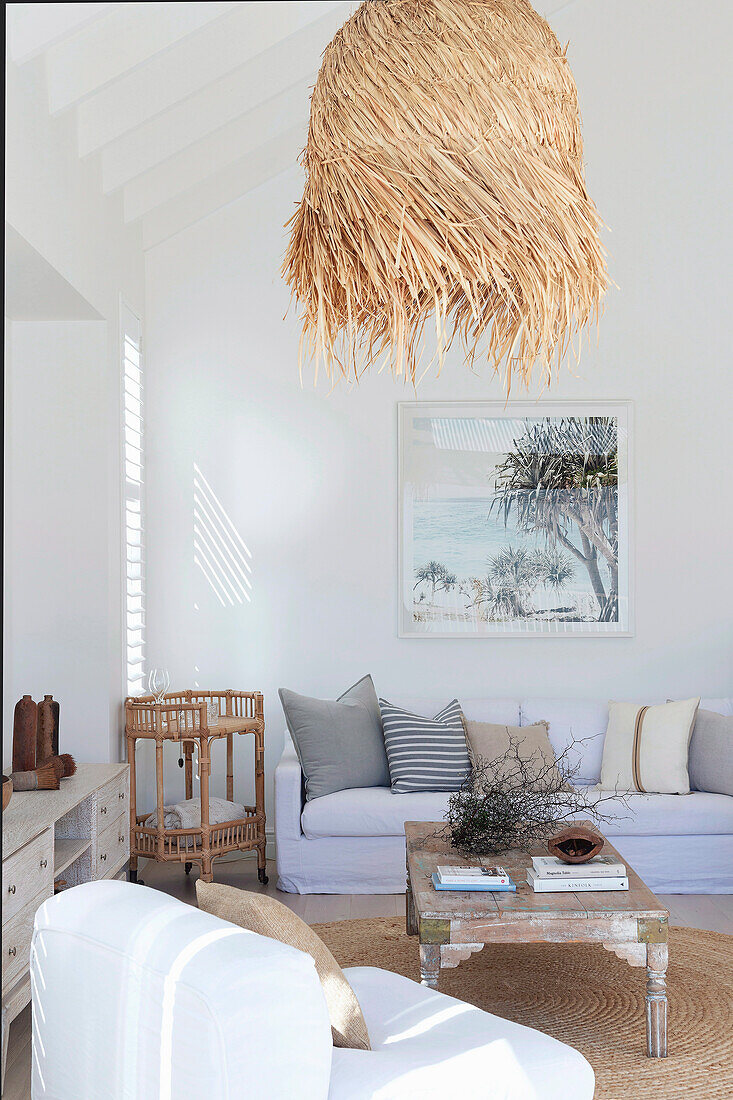Sitting area in living room with high white ceiling and straw pendant lamp