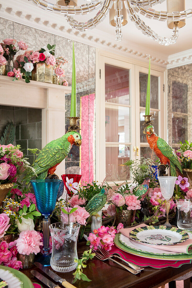 Esszimmer mit üppiger Blumendekoration, gedeckter Tisch mit Papagei-Skulptur als Kerzenhalter