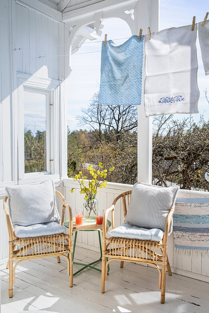 Sitzplatz und Wäscheleine mit Tüchern auf sonniger Veranda