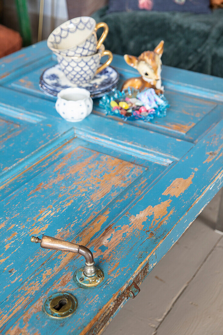 Coffee cups and deer figurine on blue-painted door as table